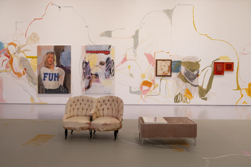 canvases hung on gallery wall, with lined paintings of figures spilling out over the wall. A sofa and coffee table sits in the foreground