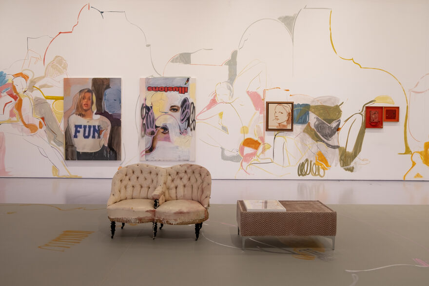 canvases hung on gallery wall, with lined paintings of figures spilling out over the wall. A sofa and coffee table sits in the foreground