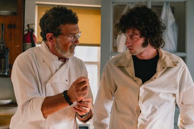 Two chefs talk in a kitchen