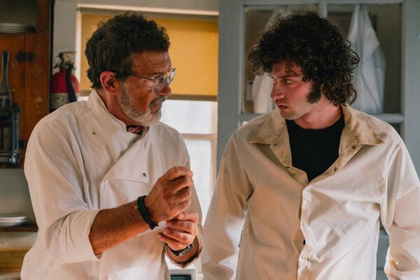 Two chefs talk in a kitchen