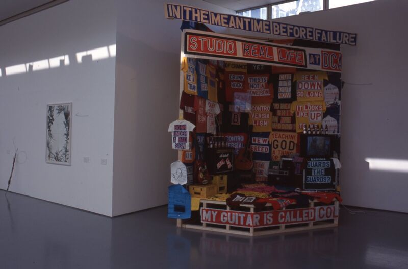 A colourful stall covered in t-shirts with slogans written on them.
