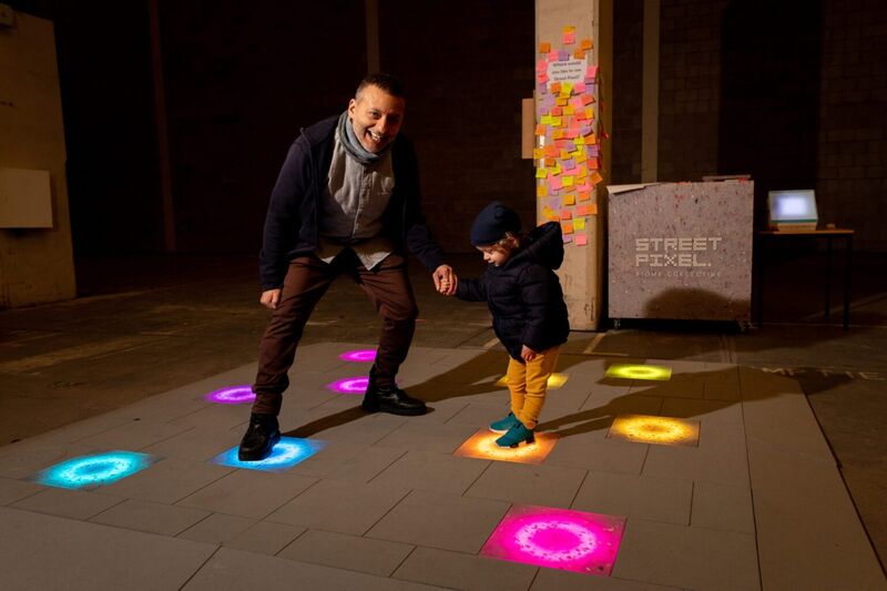 Adult and child stepping on Biome Collective's light up floor