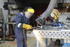 A person welds using a blow torch in a metal workshop