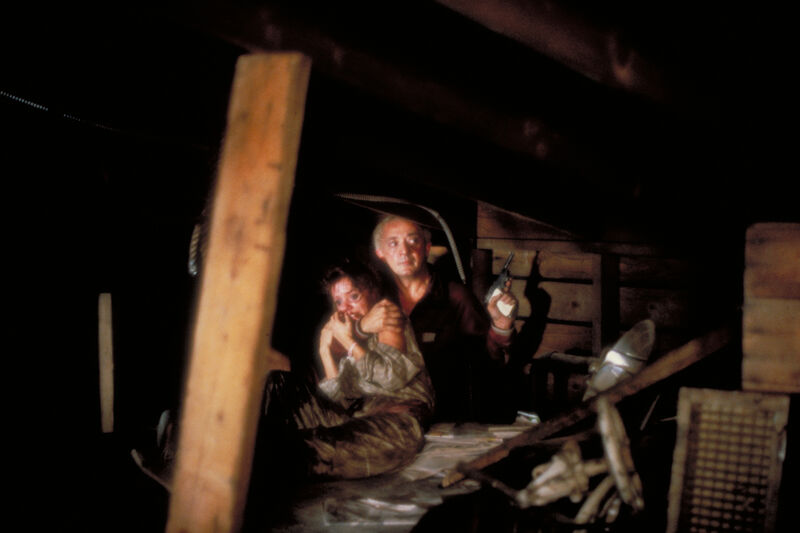 Man holding a woman who looks afraid and a gun