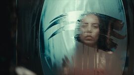 A woman looks into a smudged mirror