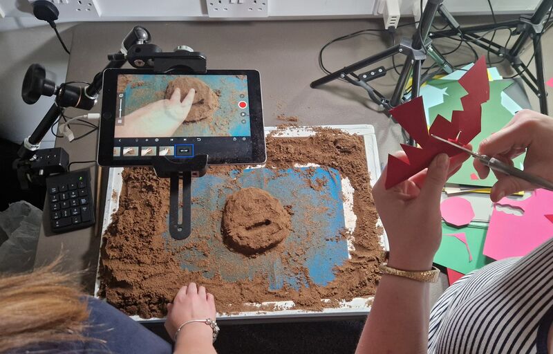 People making animations using sand and hand cut papaer