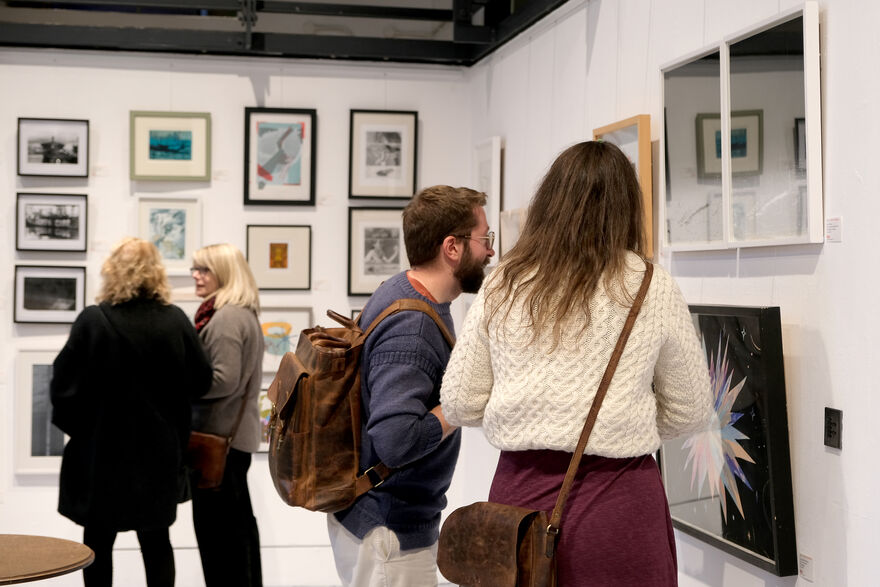 People looking at prints hanfging on teh wall of Centrespace
