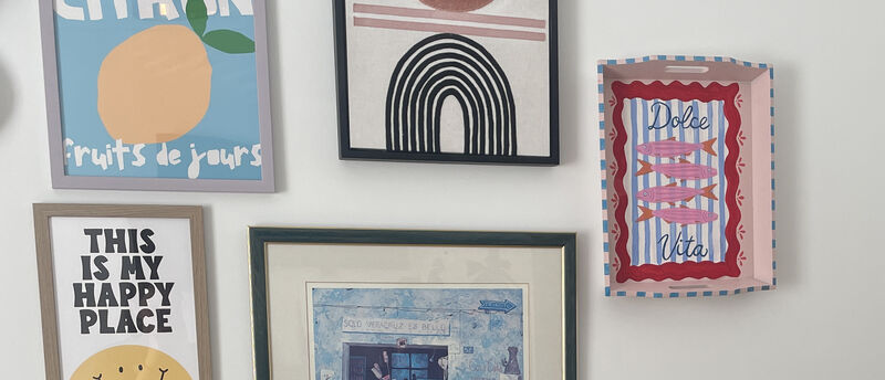 Painted tray displayed on wall beside framed prints