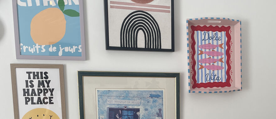 Painted tray displayed on wall beside framed prints