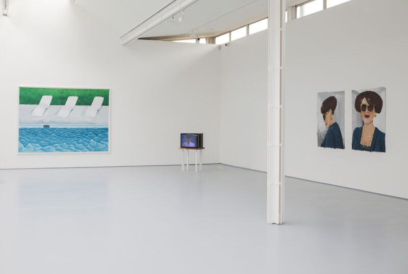 Installation image showing Gallery two, with a diptych painting on the right hand wall showing two angles of a glamorous feminine person. To the centre of the image, in the corner of the gallery, is a small CRT box monitor on a low table. On the back wall is a large colourful painting showing three white deckchairs at the side of a vivid blue swimming pool. The walls are white and the floor is grey, and there is natural light in the space. 