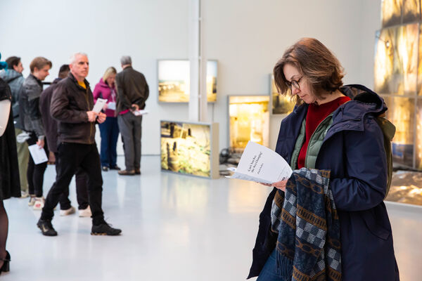 A person reads the exhibition notes in Zineb Sedira's exhibition.