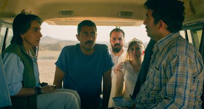  A group of people stand in the desert, talking to people in the back of a van