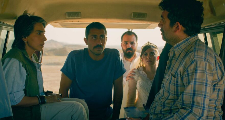  A group of people stand in the desert, talking to people in the back of a van
