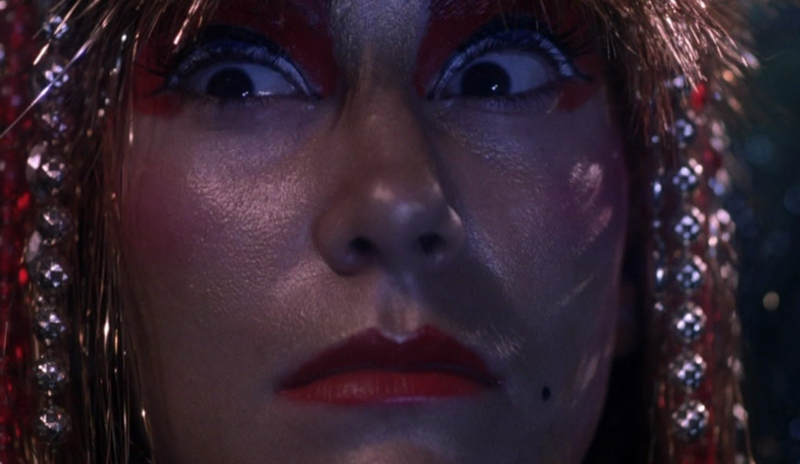 Close up of a woman's face with makeup, her hair has strings of beads