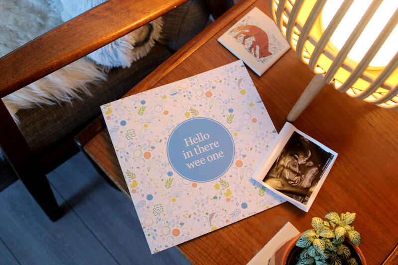 Hello in there wee one book sitting on a coffee table beside a scan image of a baby