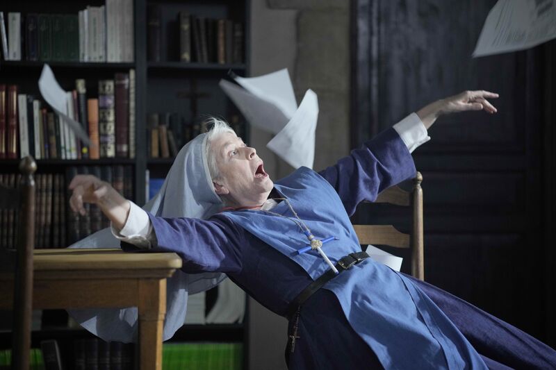 A nun falls back, looking shocked, while paper flies around her.