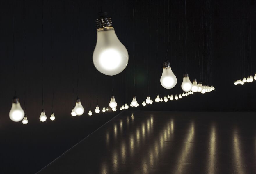 From Jim Campbell's exhibition. A close shot of tens of light bulbs suspended from the ceiling in a dark room.