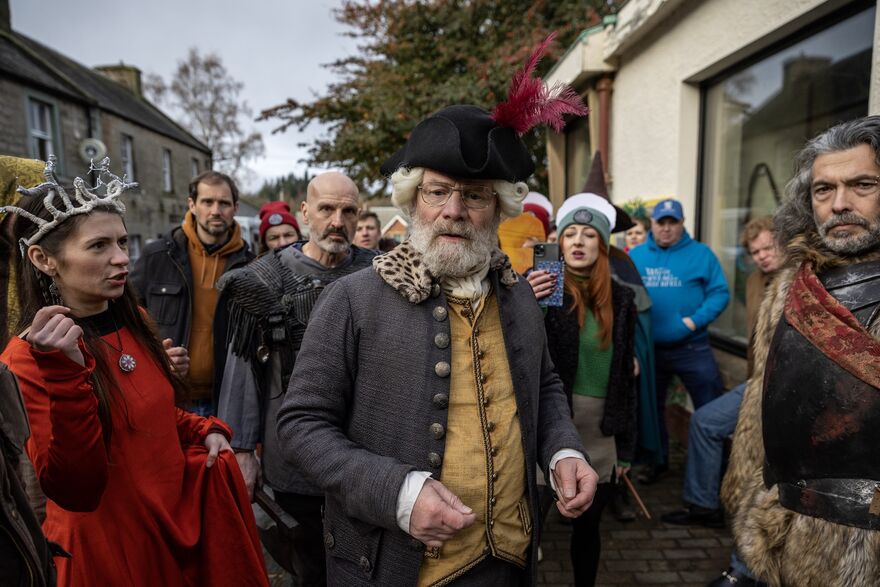 a crowd in a street, some in historical costume.