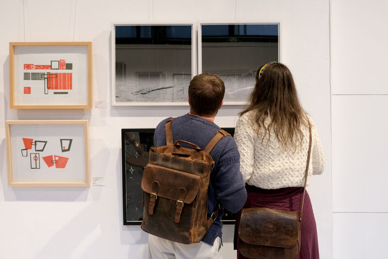 Two people looking at a series of framed prints