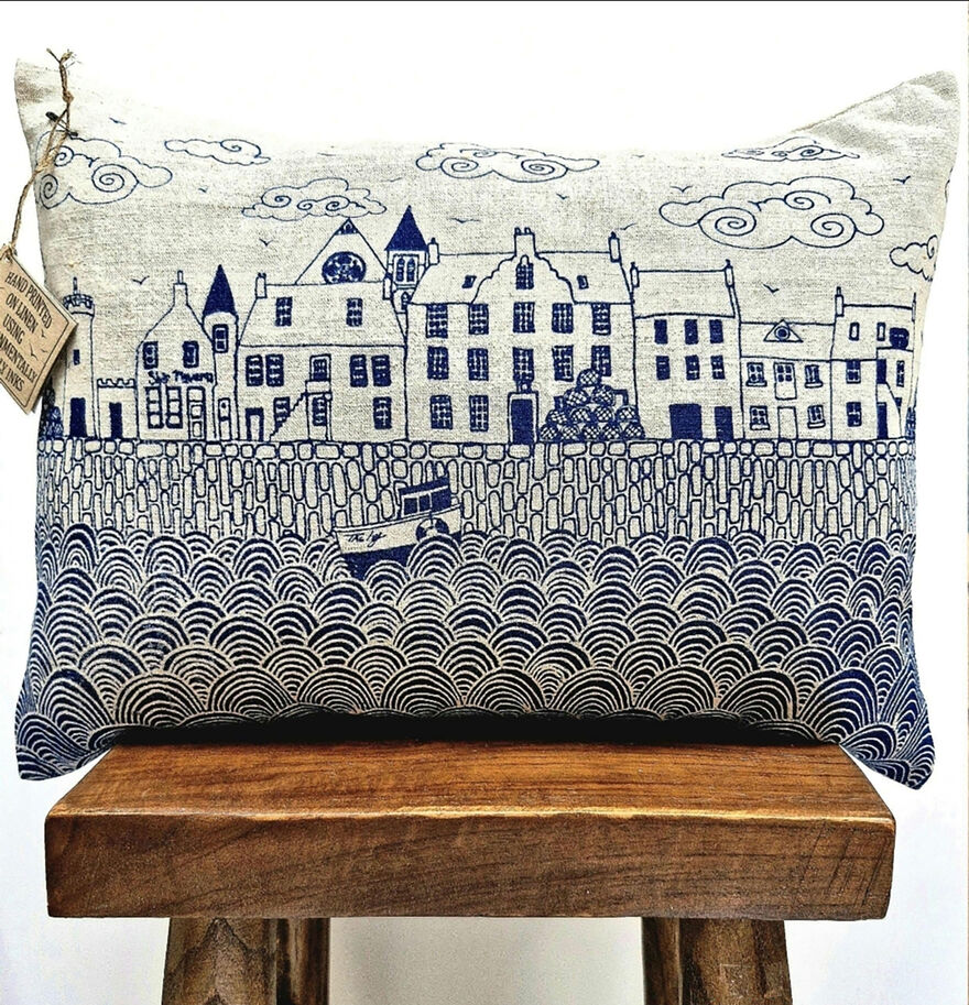 Printed cushion showing a scene of houses beside the sea