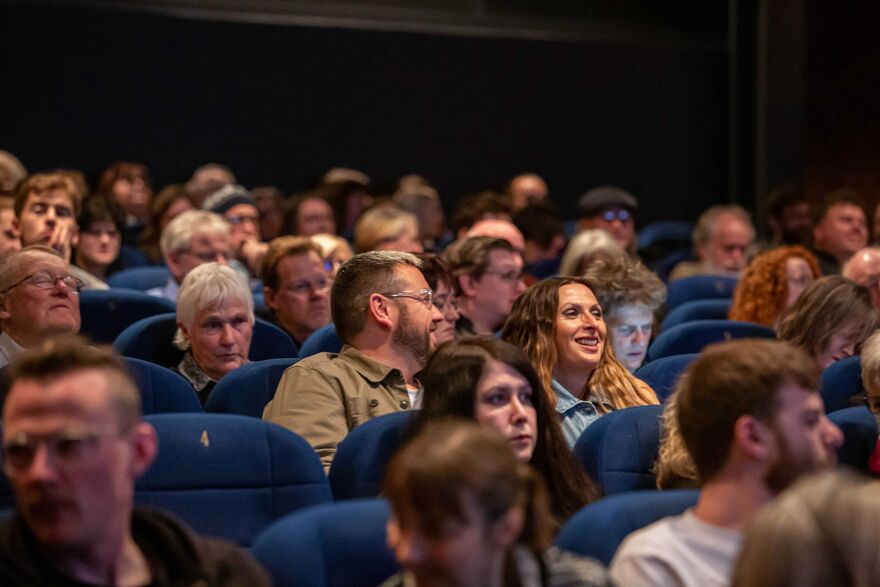 People sit in cinema seats enjoying a film.
