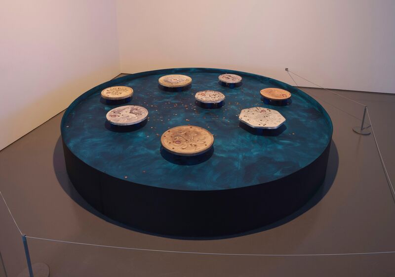 From Eddo Stern's exhibition in DCA Galleries. A large blue circle sculpture with over-sized British coins on top of it.