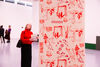 Detail of a strip of wall paper hanging from the ceiling with red images on ti