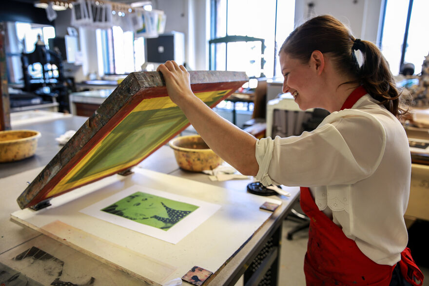 Person lifting a screen to show their screenprint