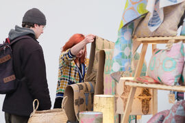 Maker showing a textile to someone at their stall