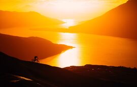 A cyclist cycling on a mountain path at sunset