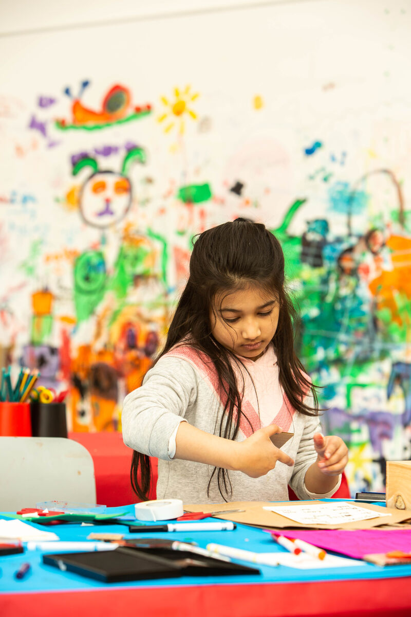 Child sitting at a table in Gallery 1 creating something out of cardboard