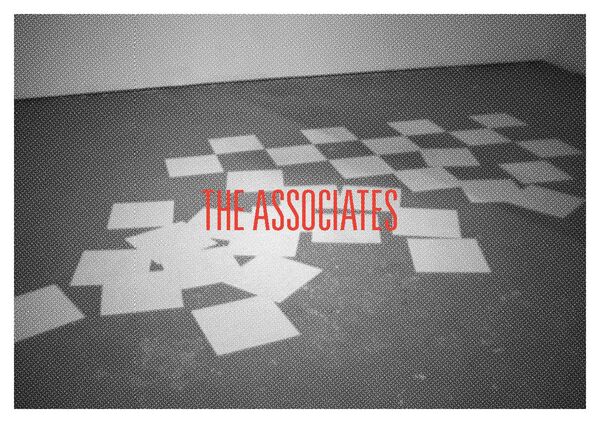 A black and white image of sheets of paper lying on the floor. In front, in red text, it say 'The Associates' 