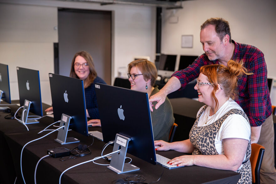 Three people at Apple Mas while instructor points at on of their screens