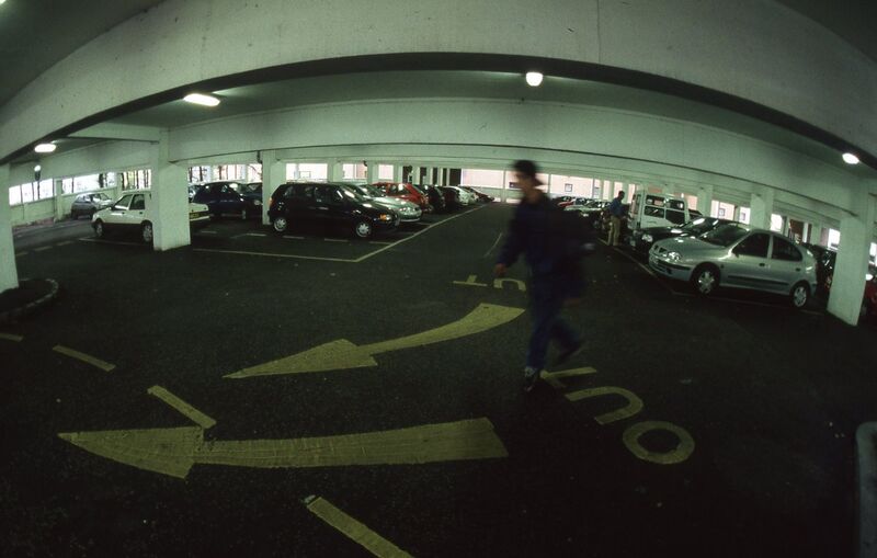 A person skateboarding in a multi-story carpark.