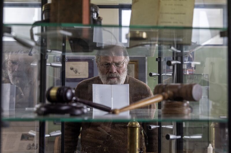 An older man in glasses looks into a museum cabinet