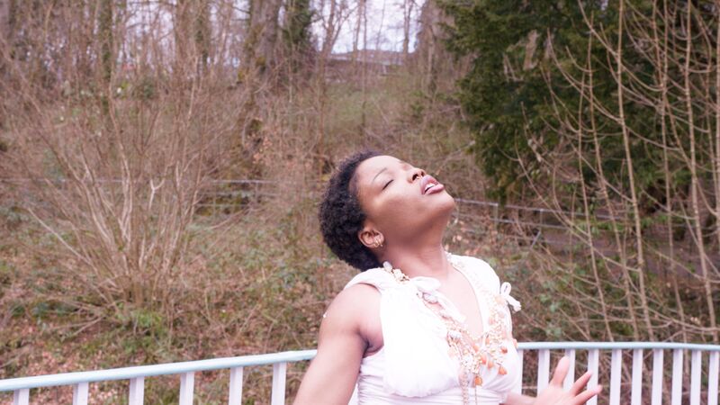 A young woman turns her head to the sky outdoors.