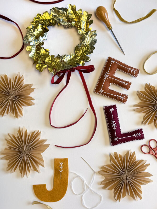 Handmade Christmas decorations including a foil wreath, hand embroidered felt letters and paper stars