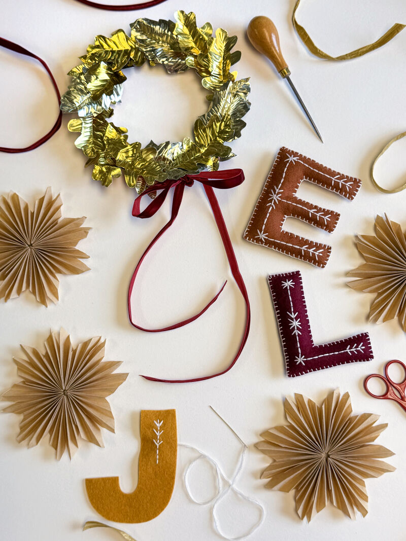 Handmade Christmas decorations including a foil wreath, hand embroidered felt letters and paper stars