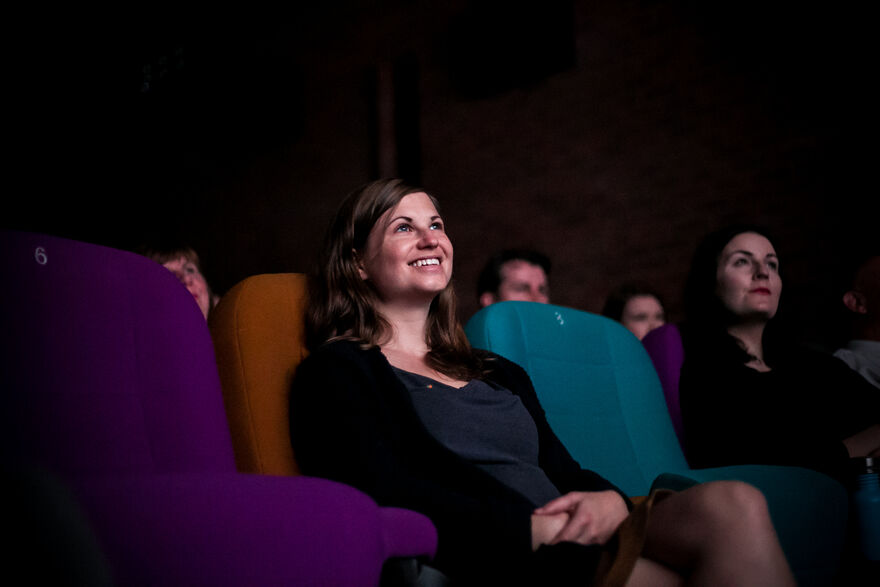 A woman smiles while sitting in a seat in the cinema.