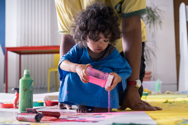 Child playing with a tub of pink sand