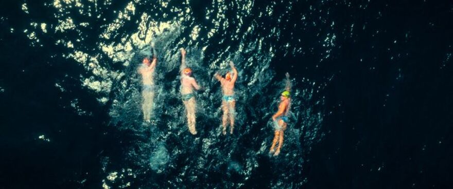 Four swimmers in a huge dark ocean