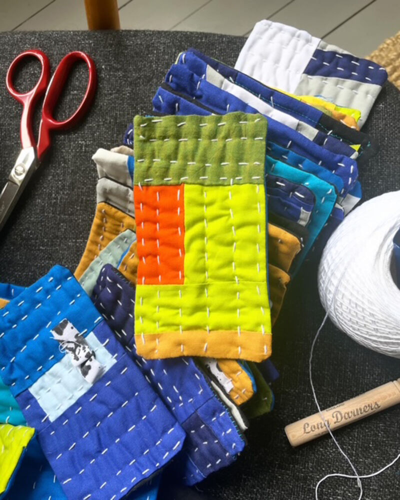 Small quilted samples beside scissors and thread