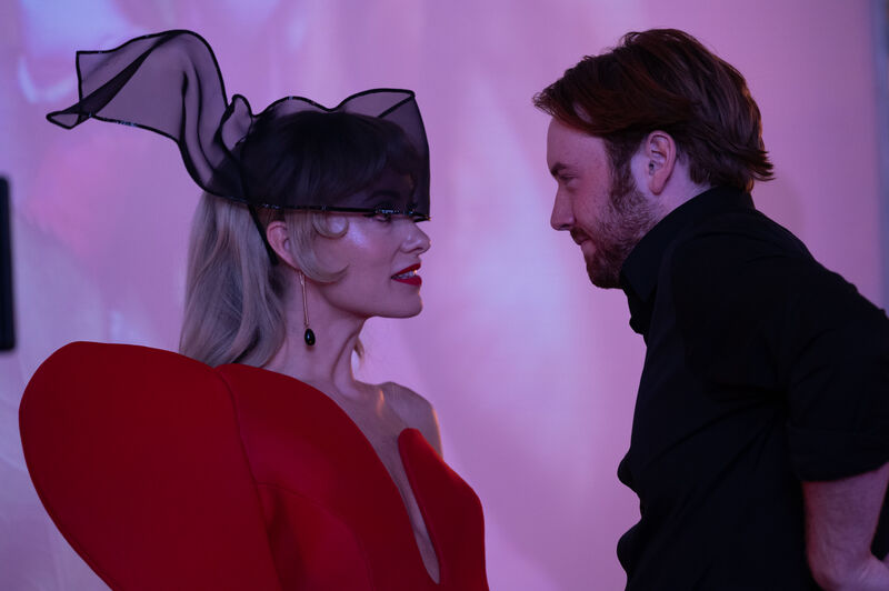 A woman in a stylish outfit talks to a young man