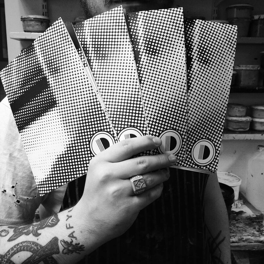 Photo of hand holding Dundee Print Collective printed materials in DCA Print Studio