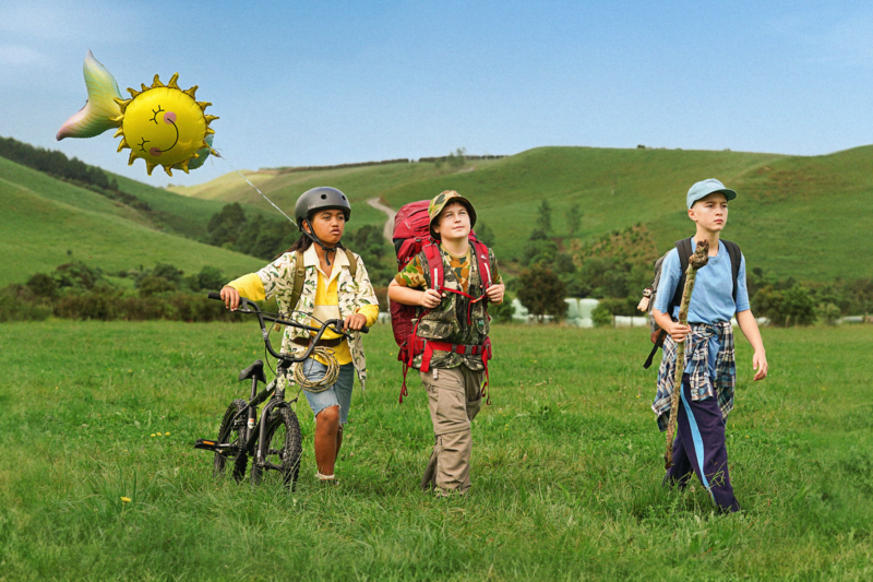 Three kids on a hike with a bike and a balloon