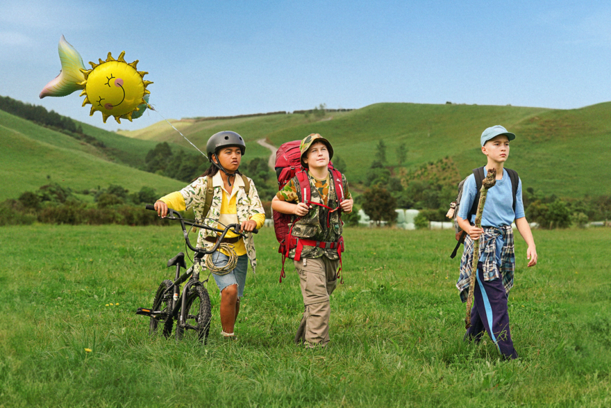 Three kids on a hike with a bike and a balloon