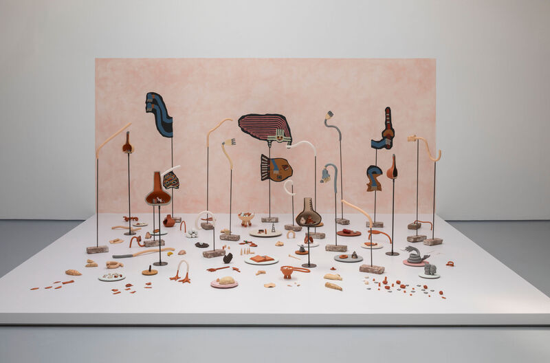 A small stage in a gallery space with clay sculptures set at different heights