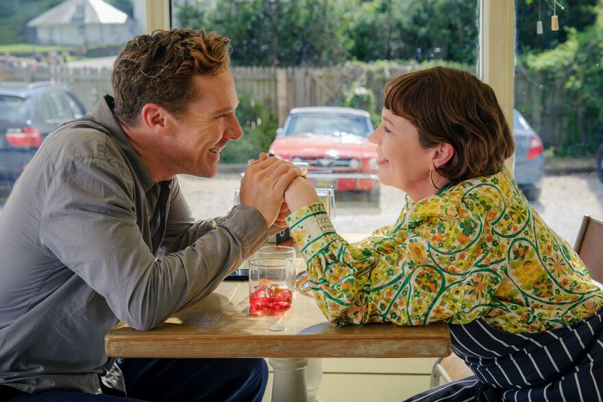 A man and woman hold hands across a table and smile.