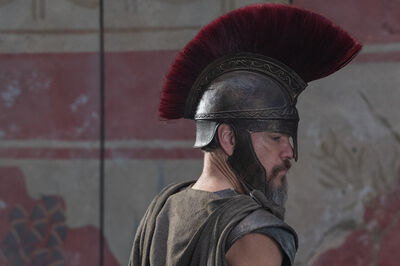 A man in a roman helmet looks to the side.