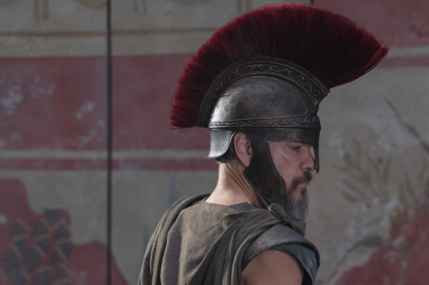 A man in a roman helmet looks to the side.